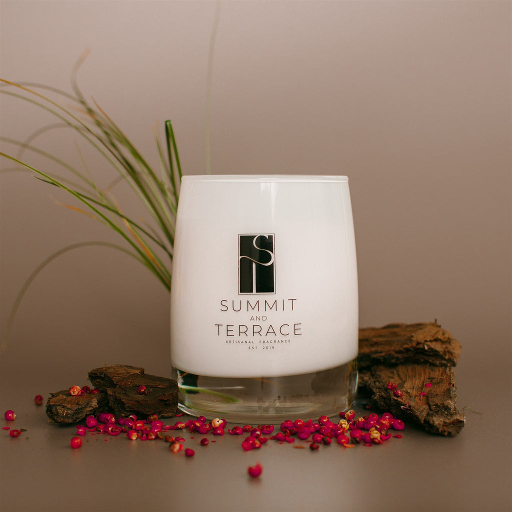Illiana Calisto Muse Classic Candle in white glass vessel with notes of mahogany, pink pepper, and wild vetiver.
