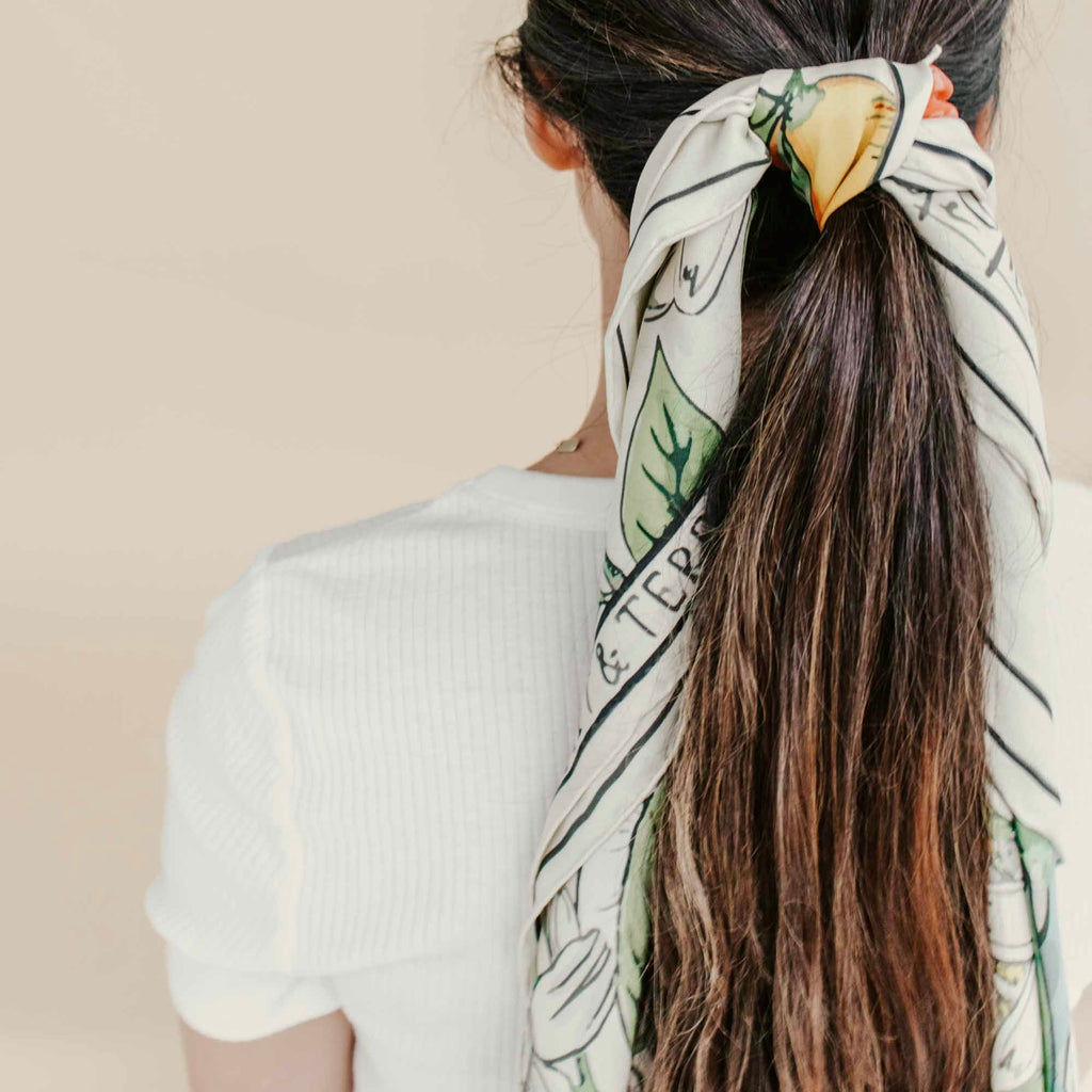 La Mia Muse Silk Twill Scarf tied in hair, featuring Mediterranean-inspired print and soft Italian silk for an effortless, elegant look.